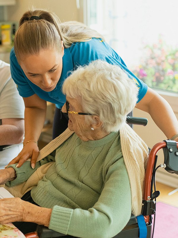 Caregiver interacting with elderly woman in wheelchair